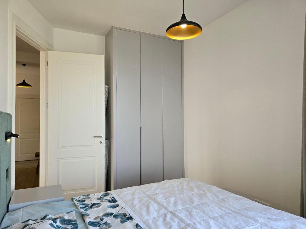 Bedroom in an apartment in Bečići, Montenegro: modern built-in wardrobe, double bed, and a stylish lamp.
