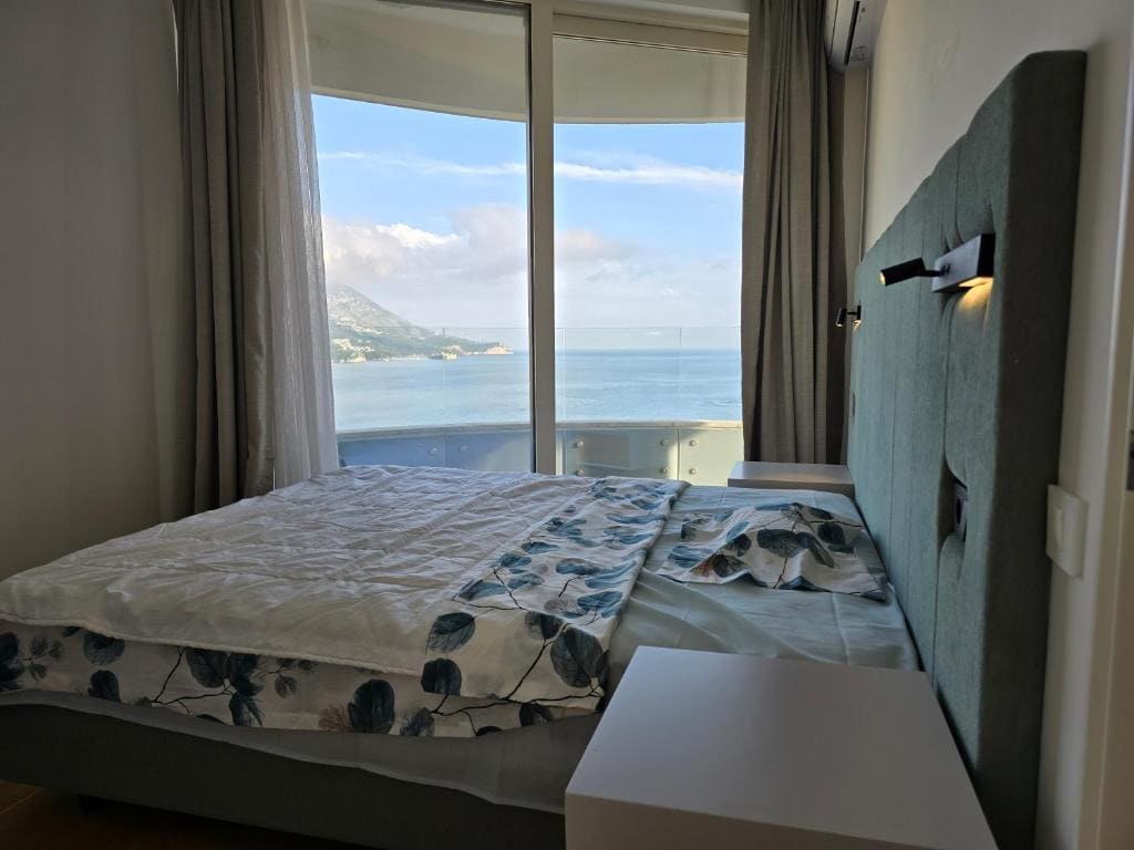 Bedroom with a double bed and panoramic sea view in an apartment, Becici, Montenegro.