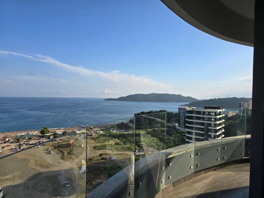 Panoramic view of the sea and Becici Beach from a modern balcony with a glass railing, Montenegro.
