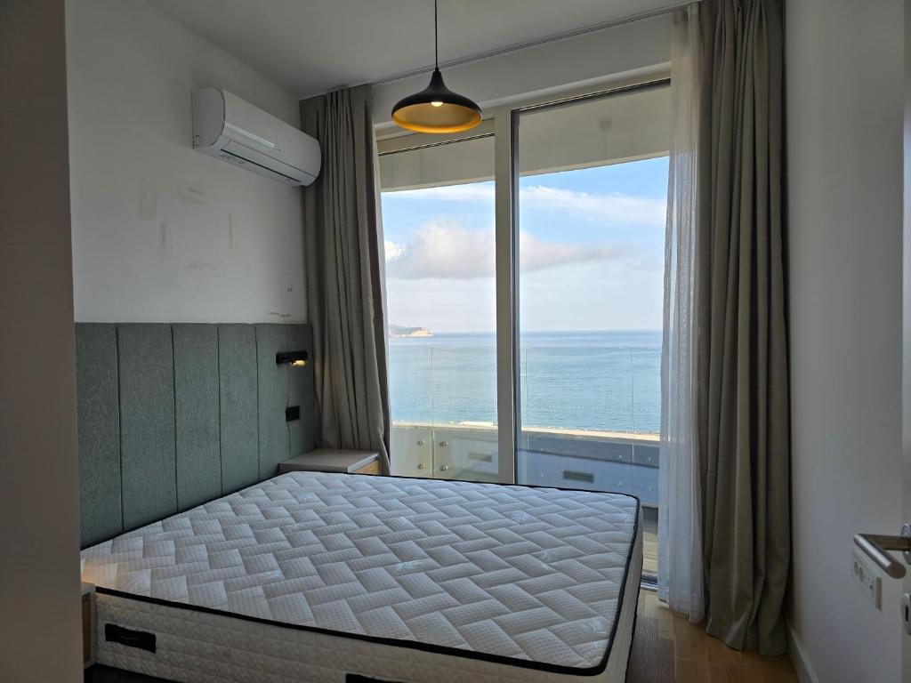 Bedroom in an apartment in Bečići, Montenegro: double bed, panoramic window with sea view, and access to the balcony.