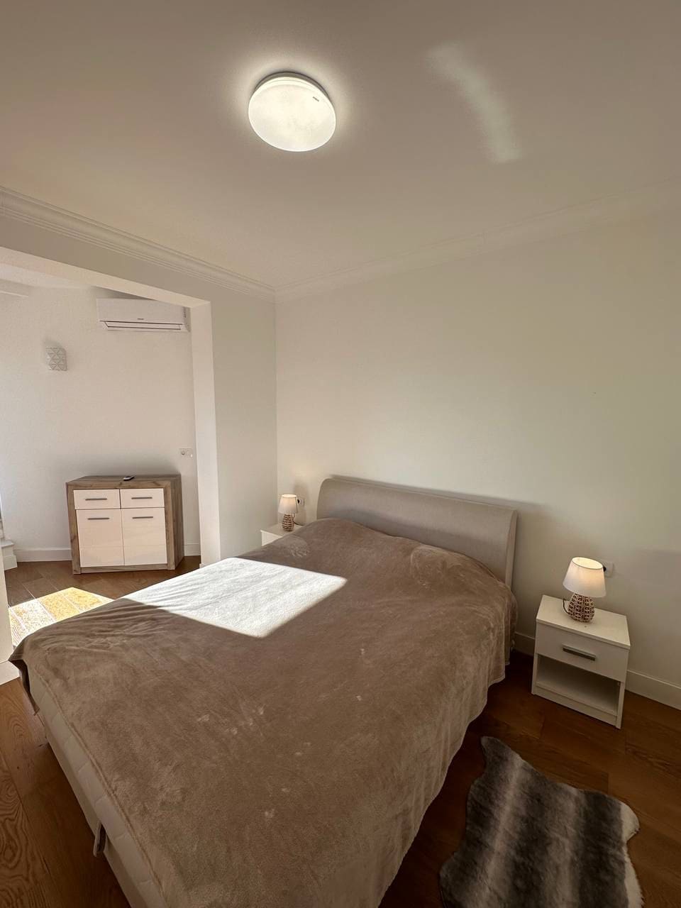Bright bedroom with a double bed and furniture in an apartment, Tivat, Montenegro. Modern interior with parquet flooring.