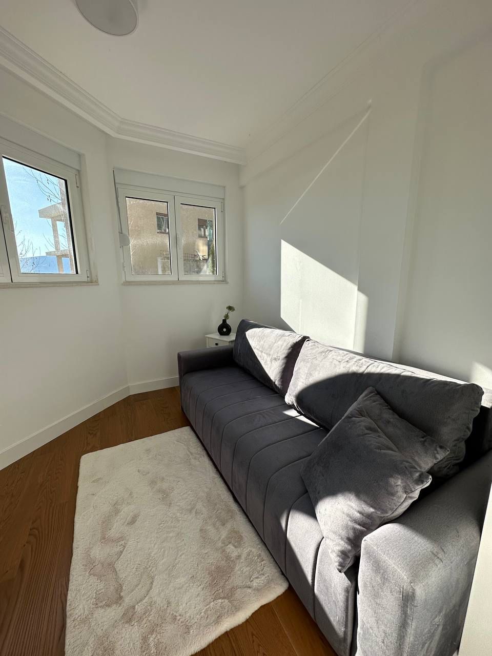 Bright living room with a gray sofa and parquet flooring in an apartment for sale in Tivat, Montenegro.