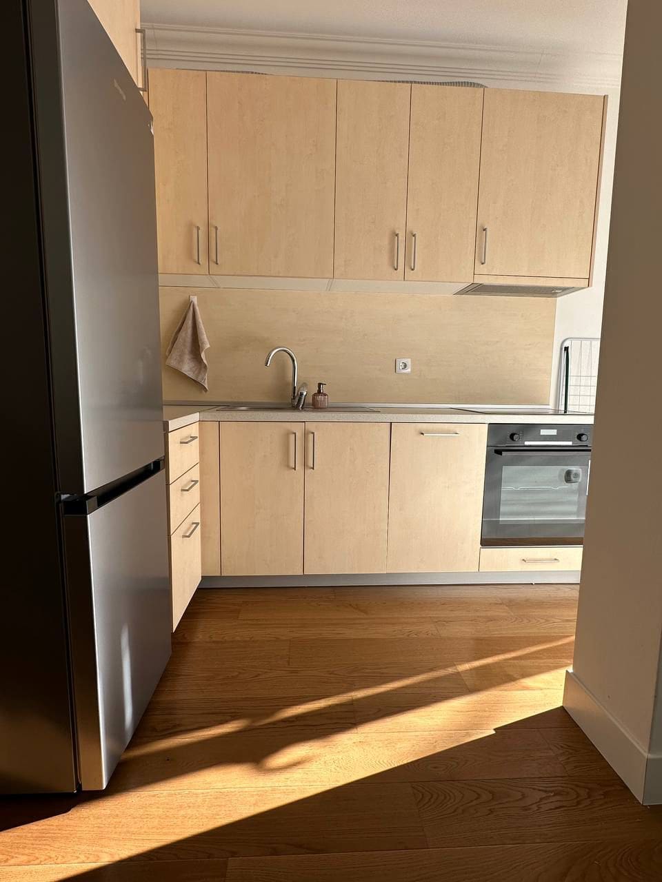 Modern bright kitchen in an apartment in Tivat, Montenegro: built-in appliances, wooden cabinet fronts, and parquet flooring.