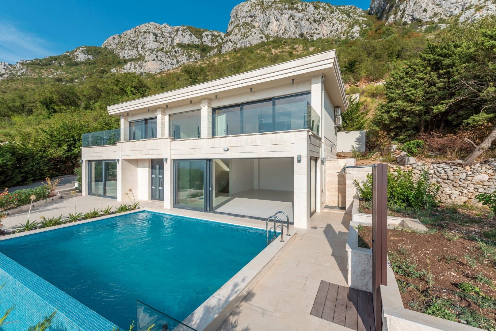 Modern villa with a pool and panoramic windows in Reževići, Montenegro: view of the house at the foot of the mountains.