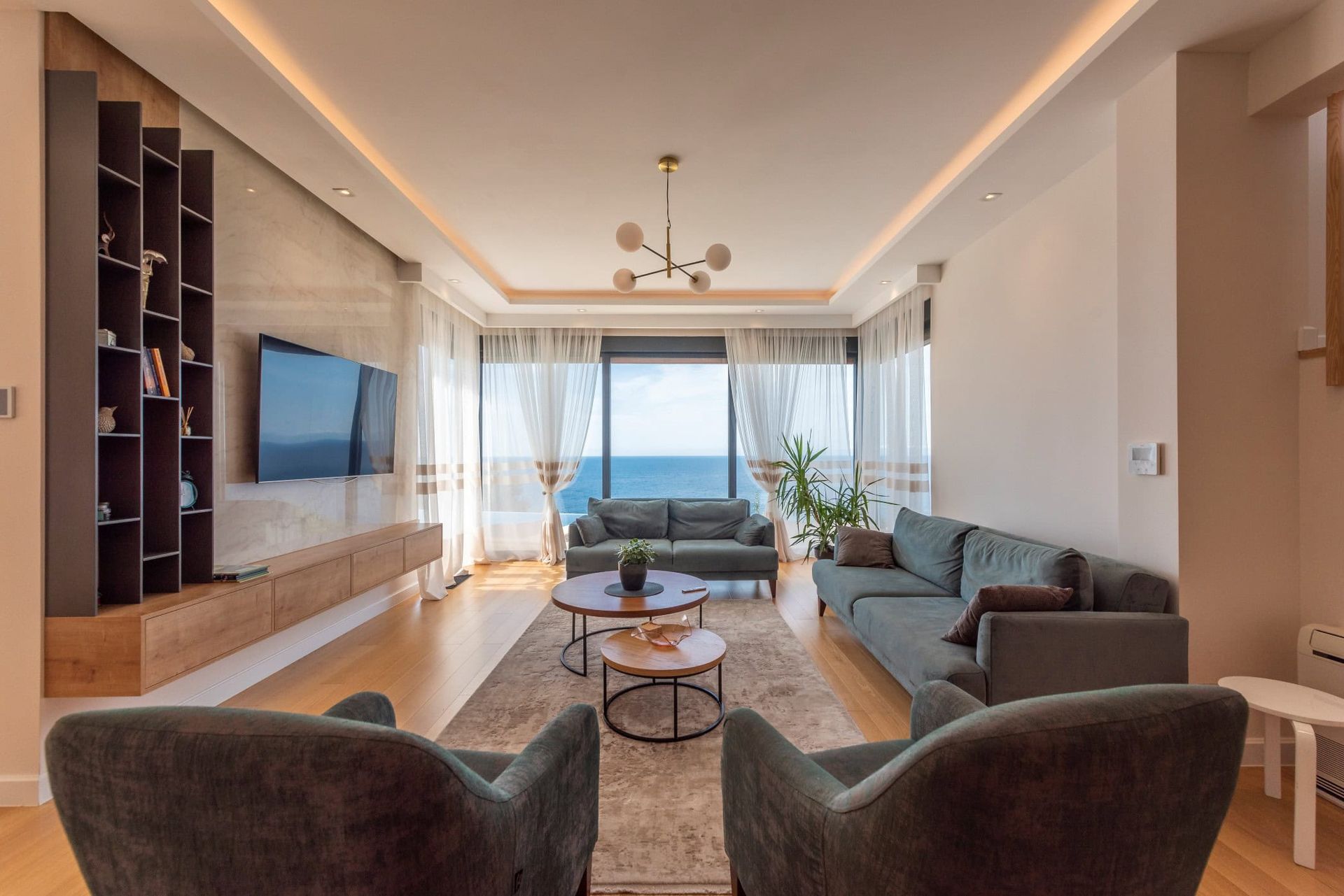 Modern living room with sea view in a house, Reževići, Montenegro: soft seating, panoramic windows, and stylish design.