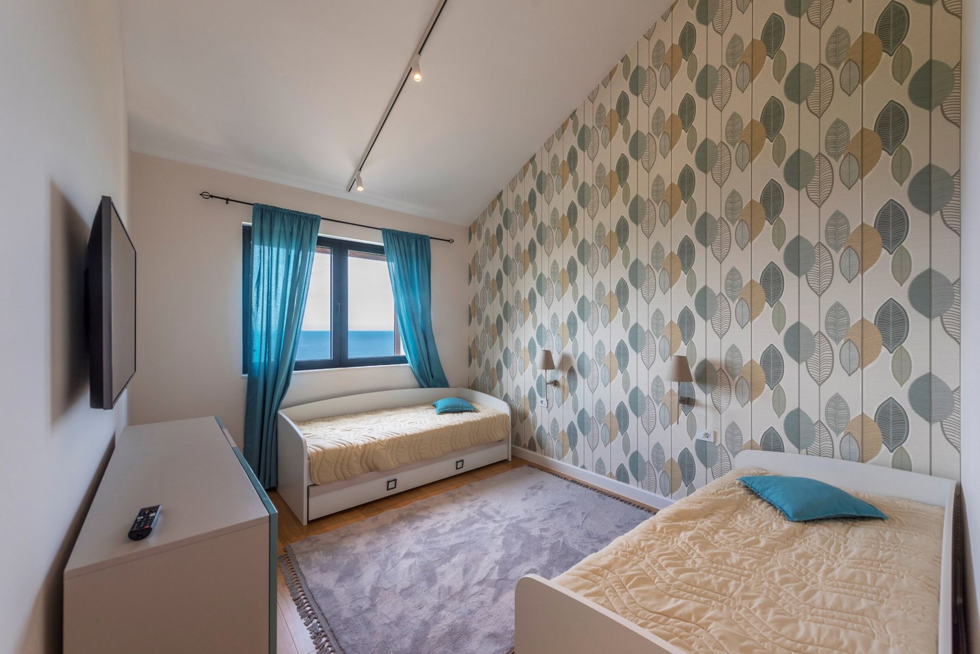 Bedroom with two beds, printed wallpaper, and sea view in a house, Reževići, Montenegro.