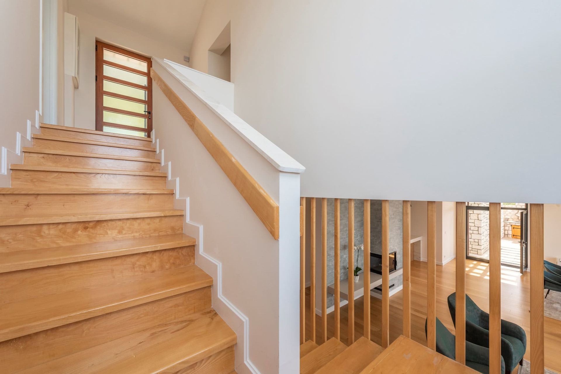 Wooden staircase in a modern house in Reževići, Montenegro: bright interior, stylish railings, and a view of the living room.