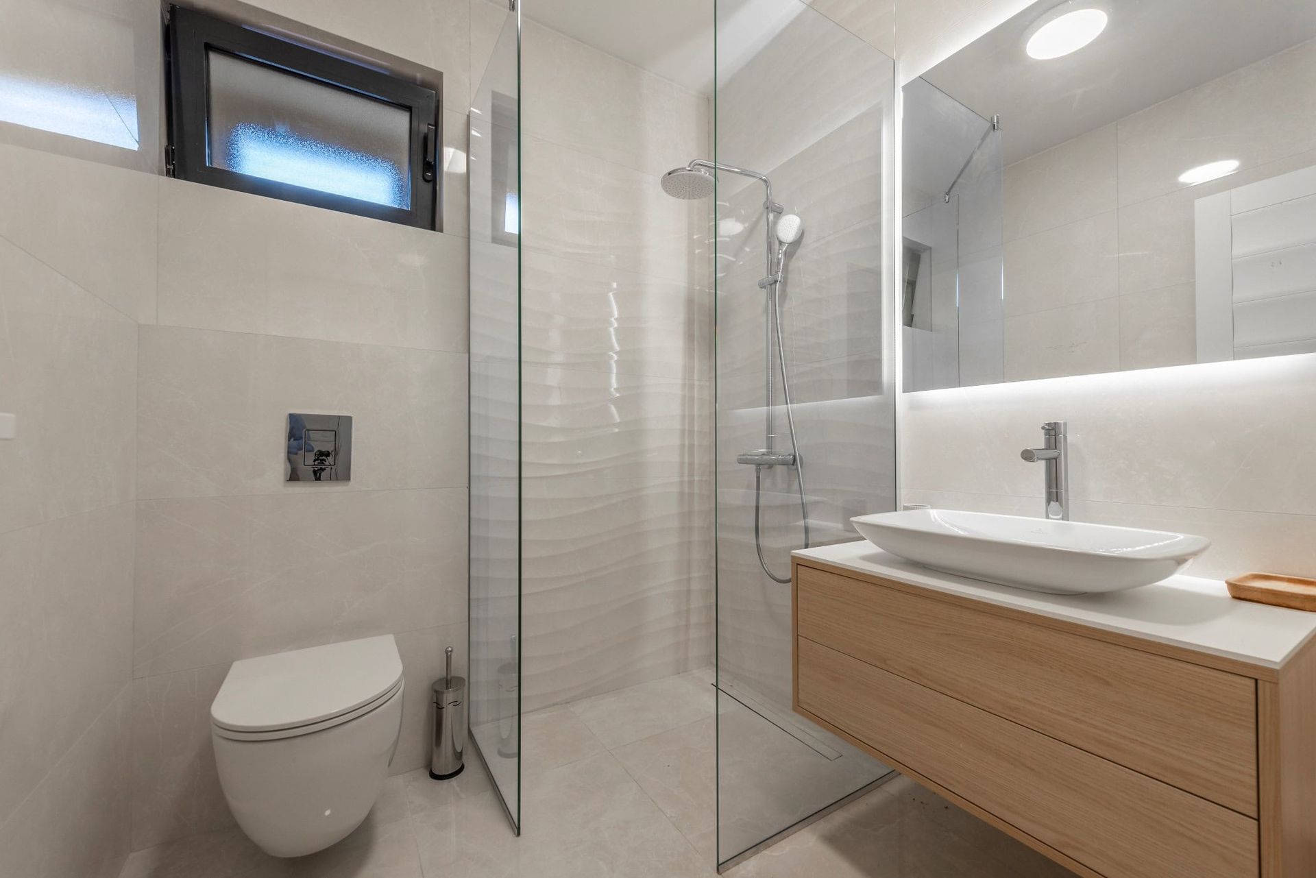 Modern bathroom in a house, Reževići, Montenegro: shower cabin, wall-mounted vanity, and light tile finish.