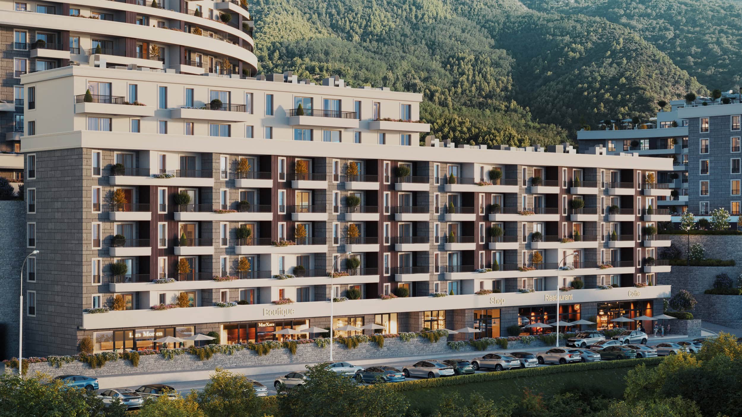 Modern residential complex in Bečići, Montenegro: facade with terraces, commercial spaces, and parking by the mountains.