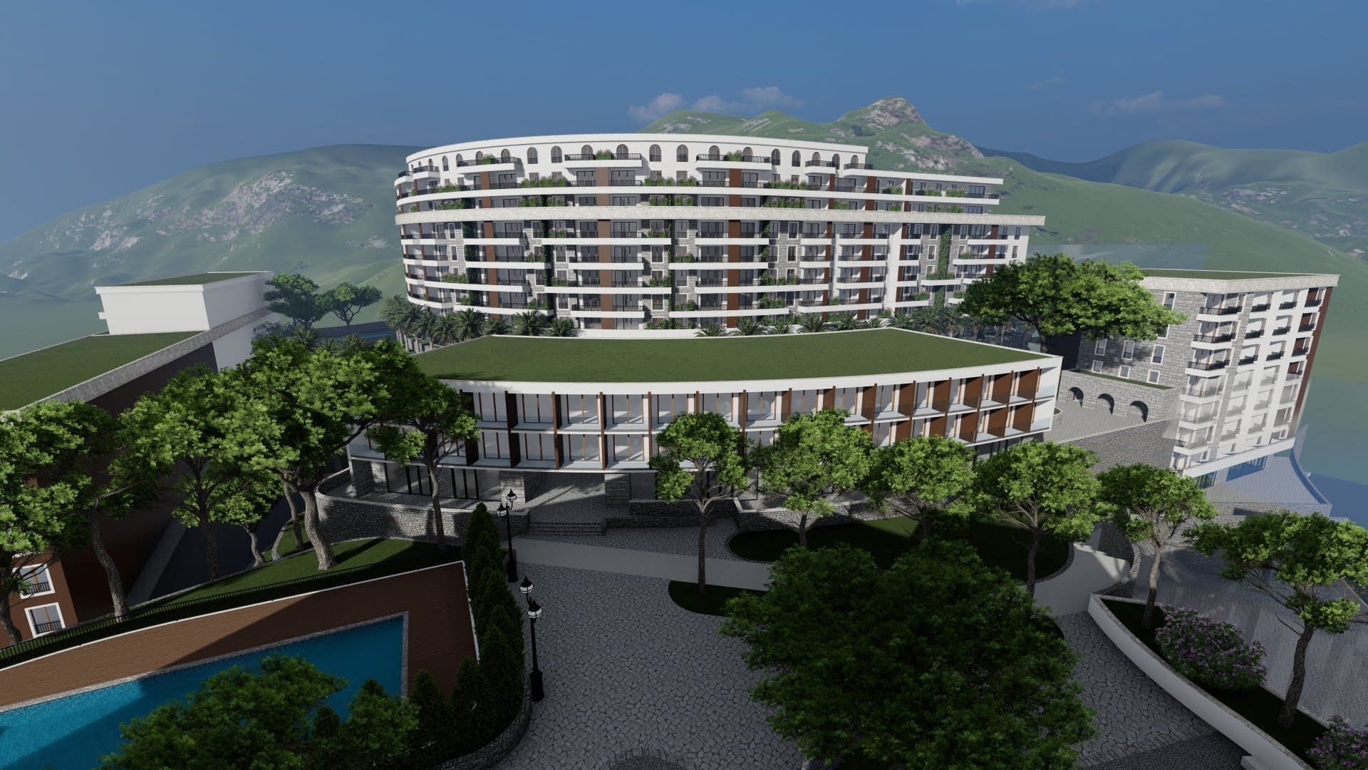 View of a modern residential complex in Bečići, Montenegro: multi-story buildings with terraces, a swimming pool, and a mountain landscape.