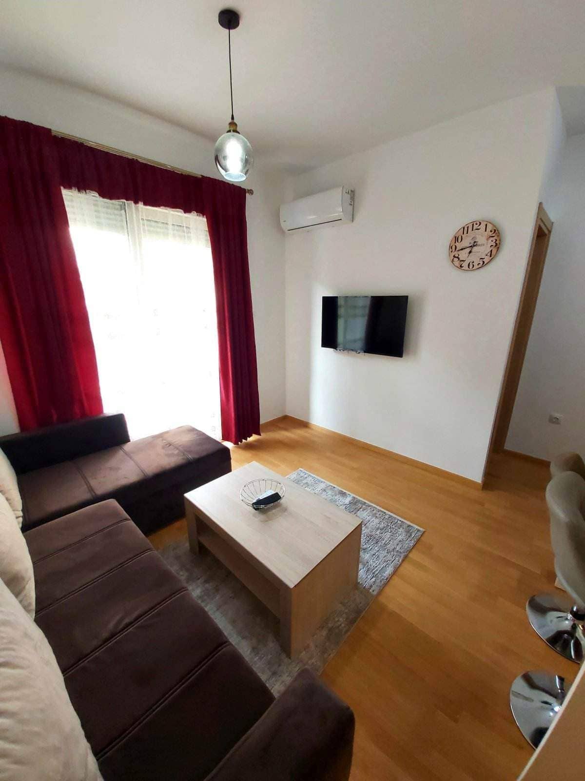 Уютная гостиная с коричневым диваном и ТВ в квартире на продажу в Будве, Черногория: современный интерьер и паркет.
