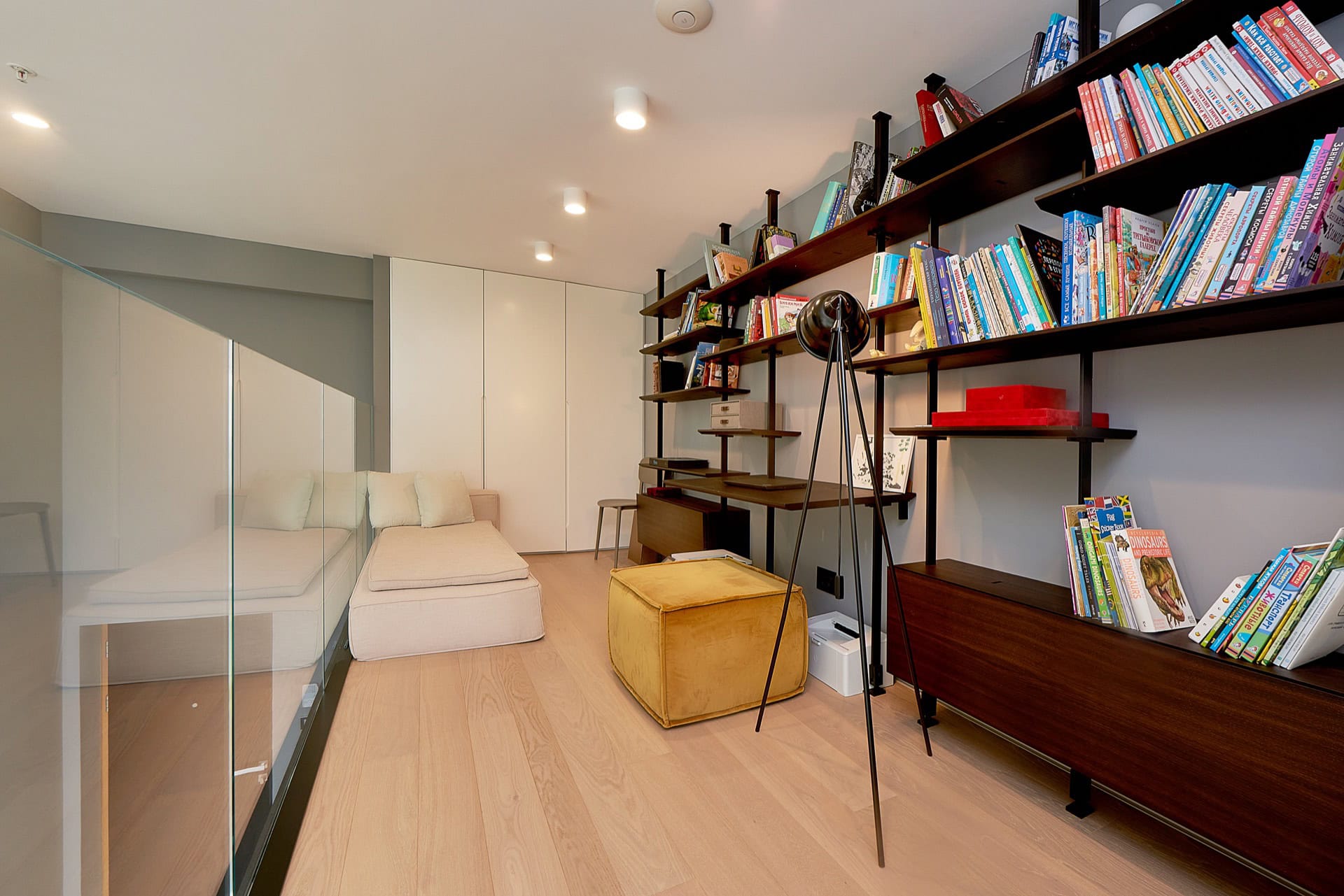 Cozy living room with a library and lounge area in an apartment, Budva, Montenegro: bright interior, shelving units, and a soft ottoman.