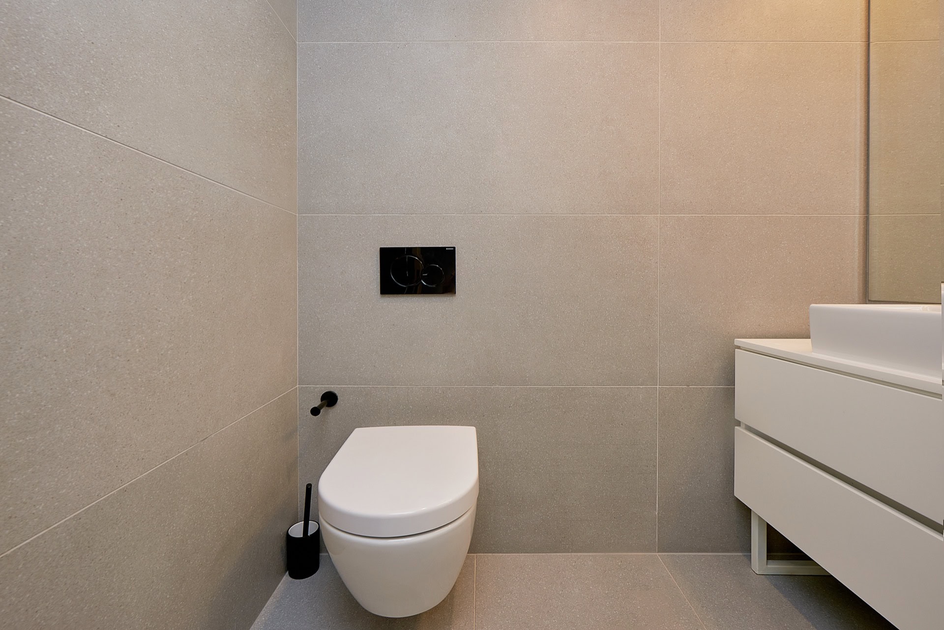 Modern bathroom in an apartment in Budva, Montenegro: wall-mounted toilet, white vanity, and porcelain stoneware.