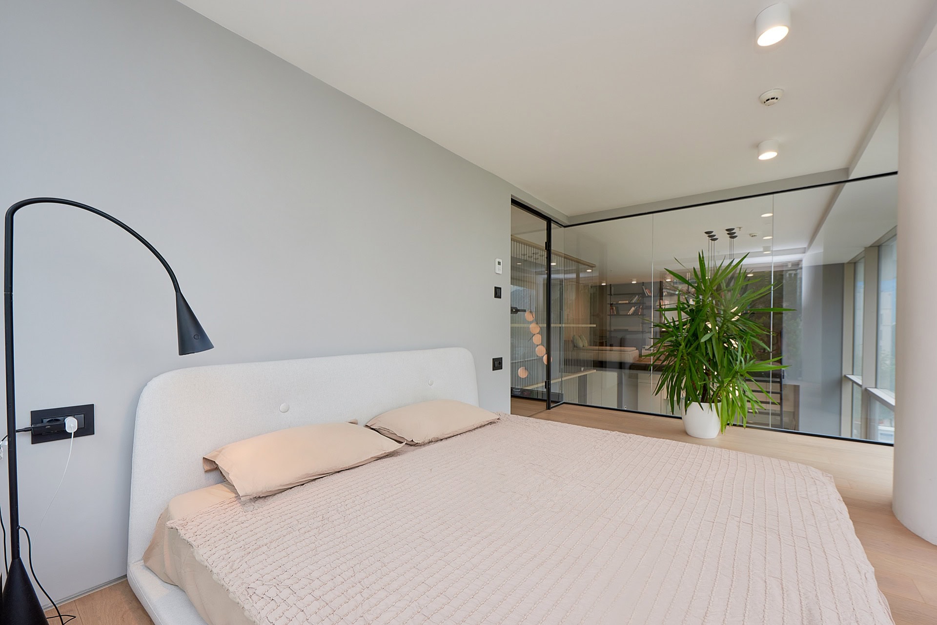 Modern bedroom with a double bed and a glass partition in an apartment in the center of Budva, Montenegro.