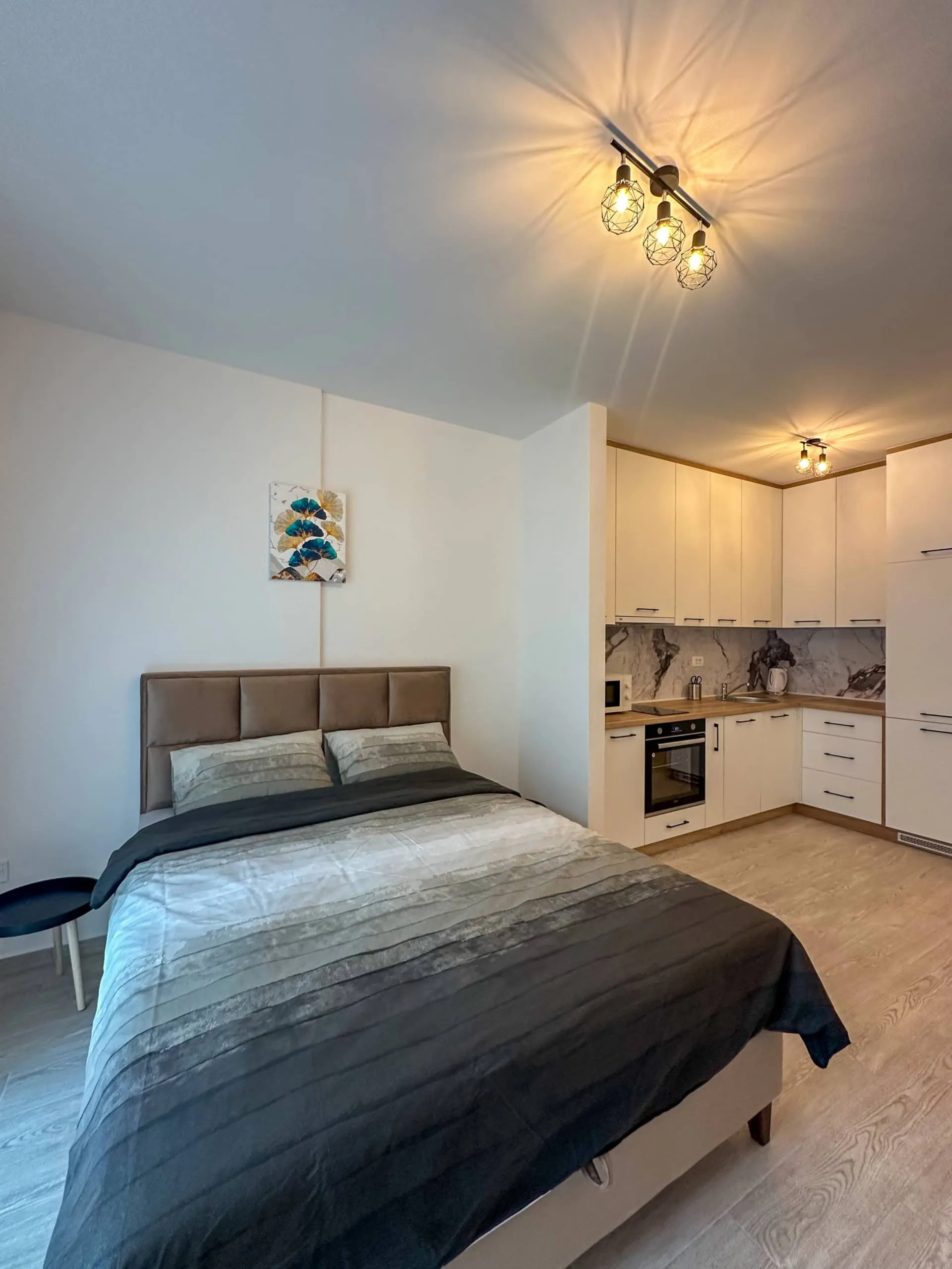 Open studio apartment showing a bed in the foreground and a kitchen area in the background.