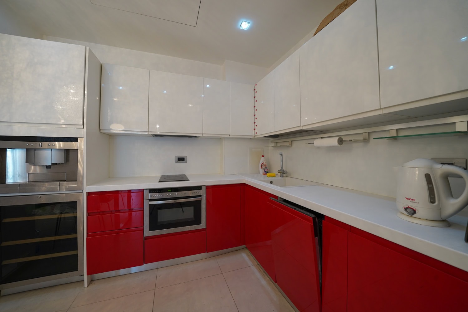 Modern kitchen with red and white cabinets in an apartment, Budva, Montenegro: built-in appliances and a bright interior.