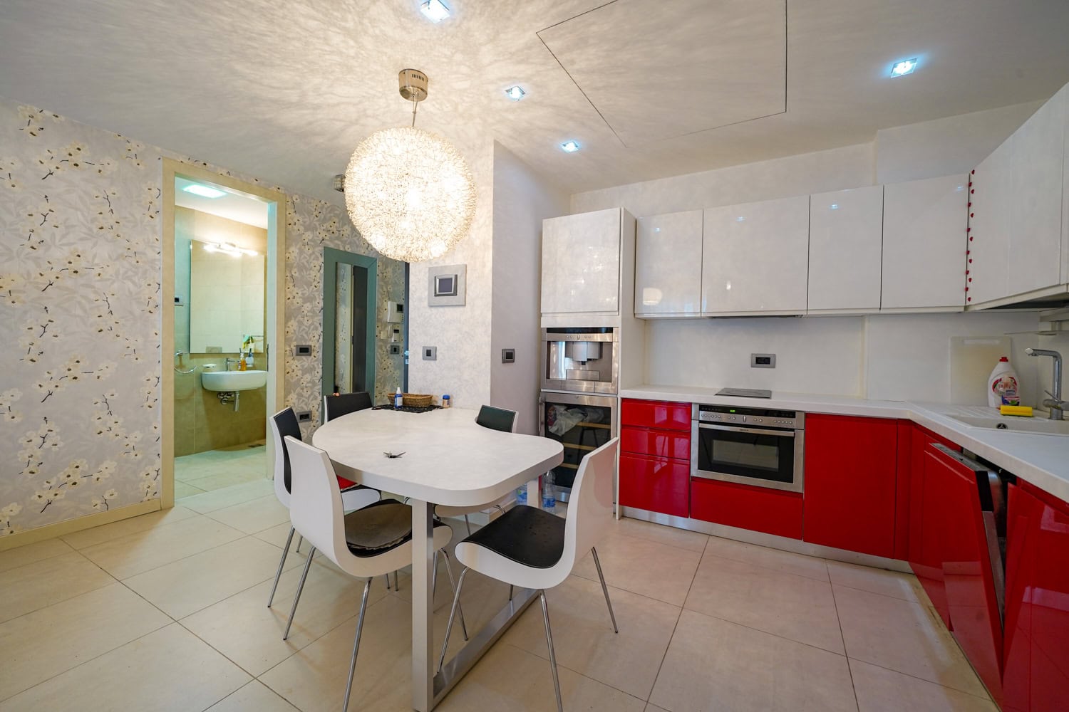 Modern kitchen-dining room with a red fitted kitchen in an apartment, Budva, Montenegro: dining area and built-in appliances.