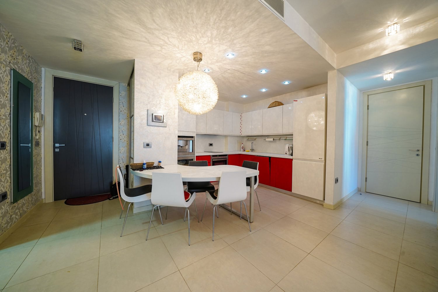 Modern kitchen-dining room with white cabinetry in an apartment in Budva, Montenegro: dining area and built-in appliances.