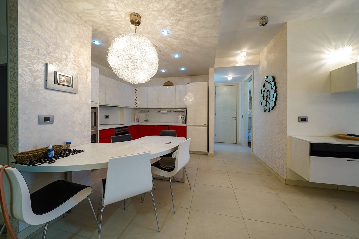 Modern kitchen-dining room with a white fitted kitchen in an apartment in Budva, Montenegro: dining area and stylish lighting.
