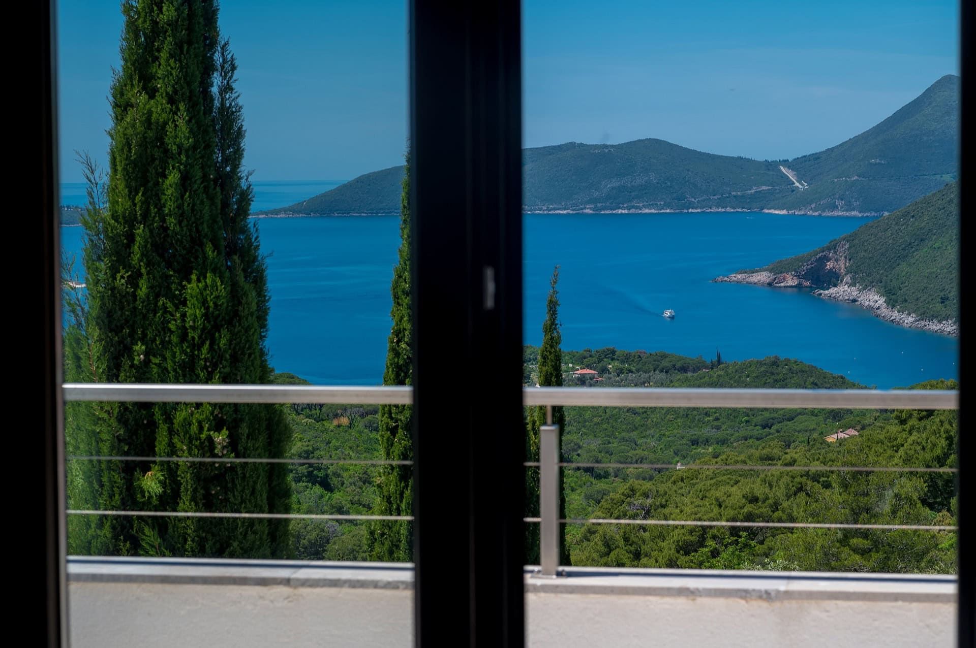 View from the villa balcony in Zanjice, Montenegro: a panorama of the Adriatic Sea, mountains, and cypress trees on the Herceg Novi coast.