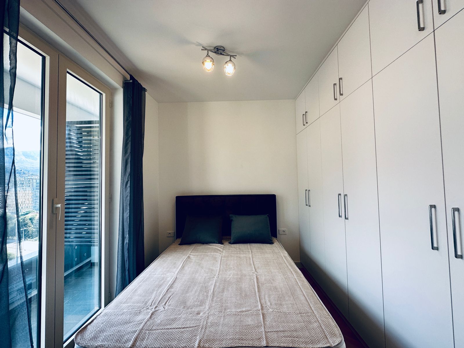Bedroom with a double bed and built-in wardrobe in an apartment in Bečići, Montenegro, with access to the balcony.
