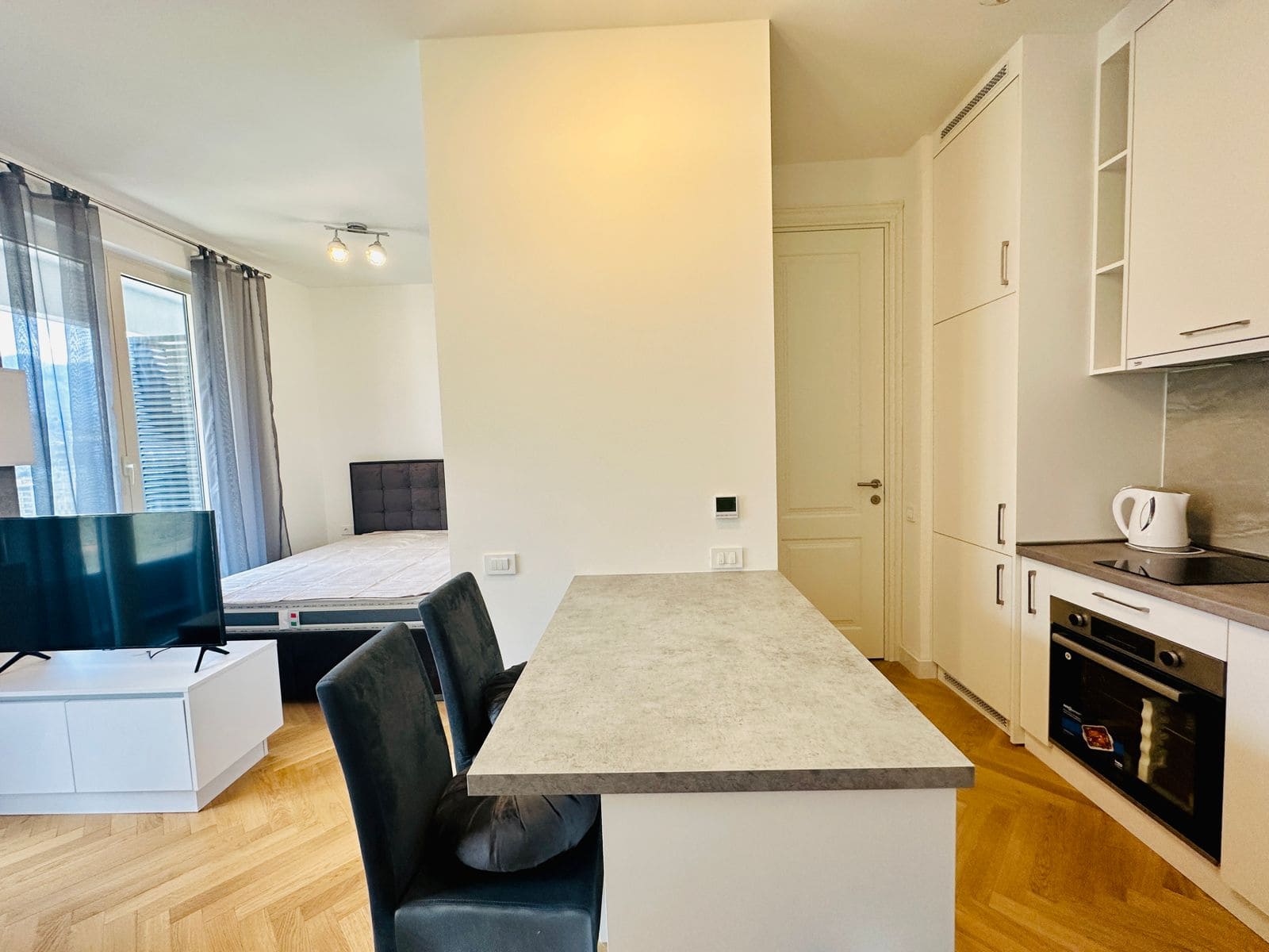 Modern studio kitchen with a breakfast bar in an apartment in Bečići, Montenegro: bright interior, built-in appliances.
