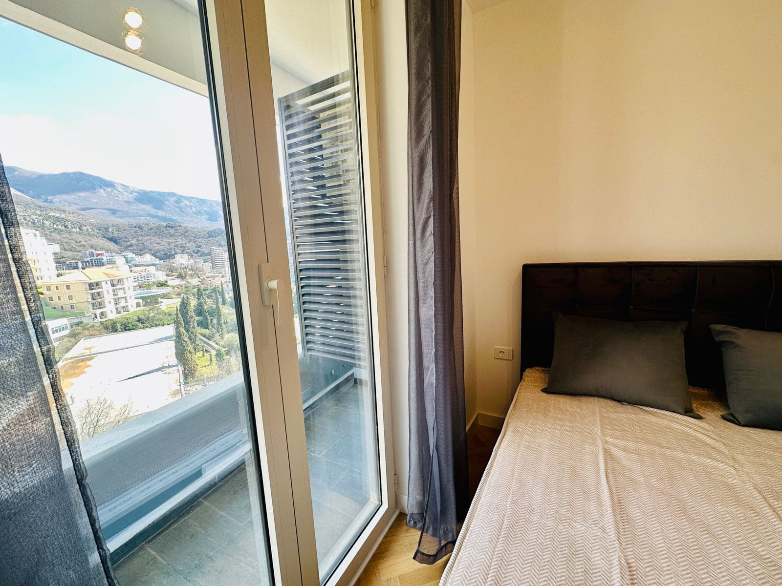 Bedroom in an apartment in Bečići, Montenegro: mountain view from the balcony, modern finishes, and a double bed.