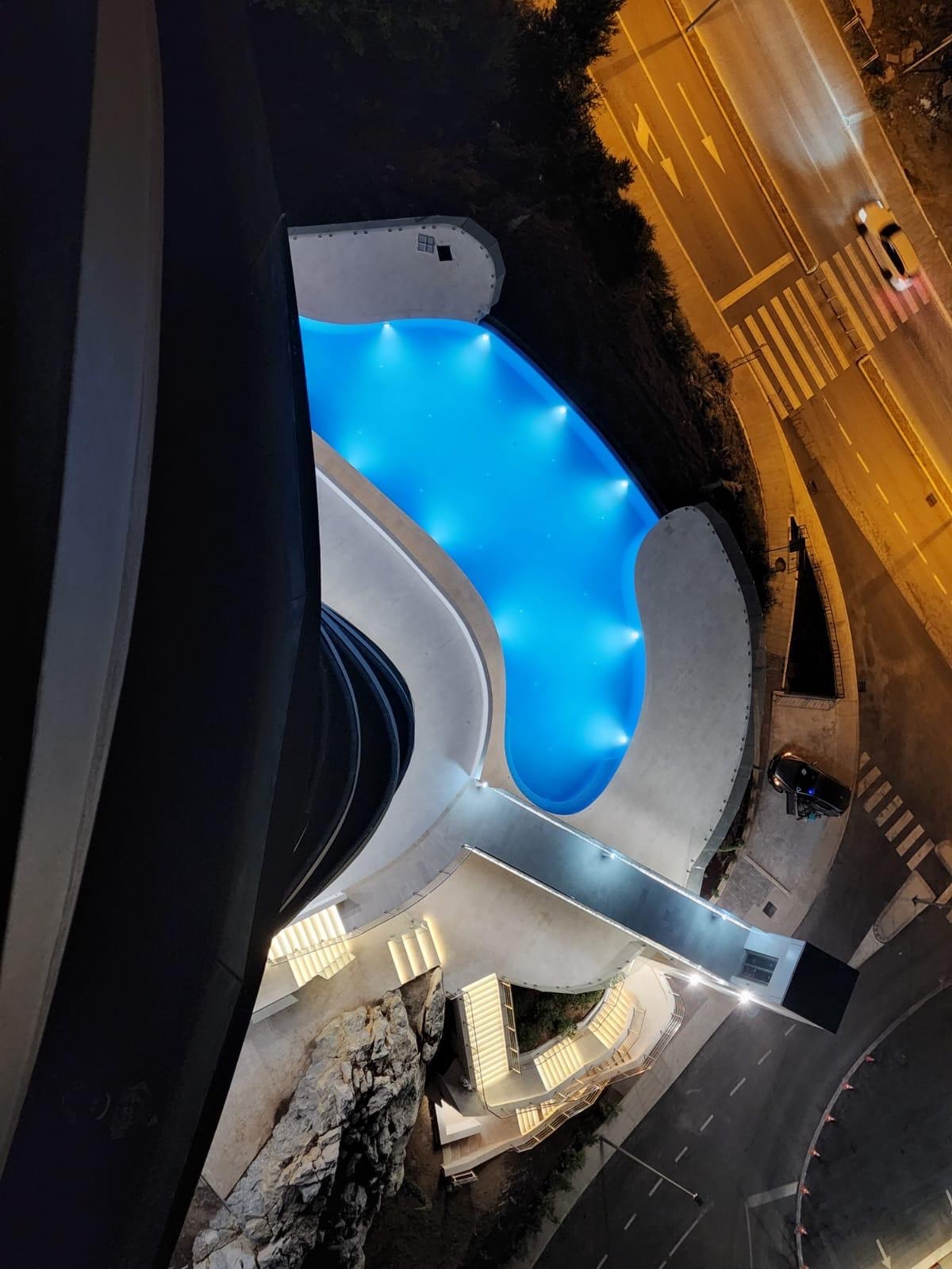 Aerial view of a modern outdoor swimming pool with lighting at an elite residence in Bečići, Montenegro.