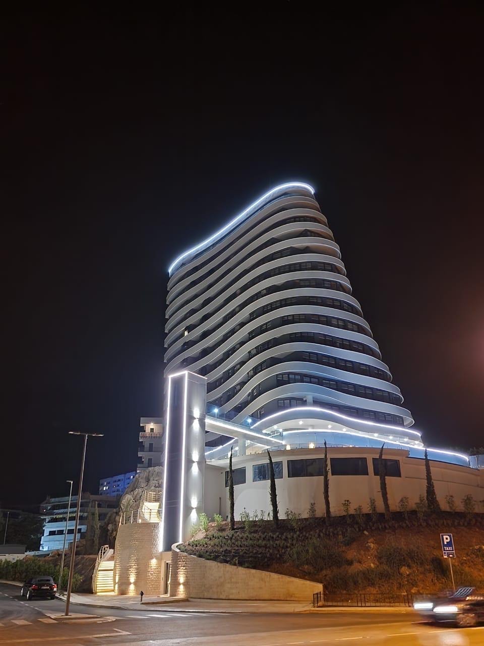 Modern multi-story building with illuminated facade and panoramic balconies in Bečići, Montenegro