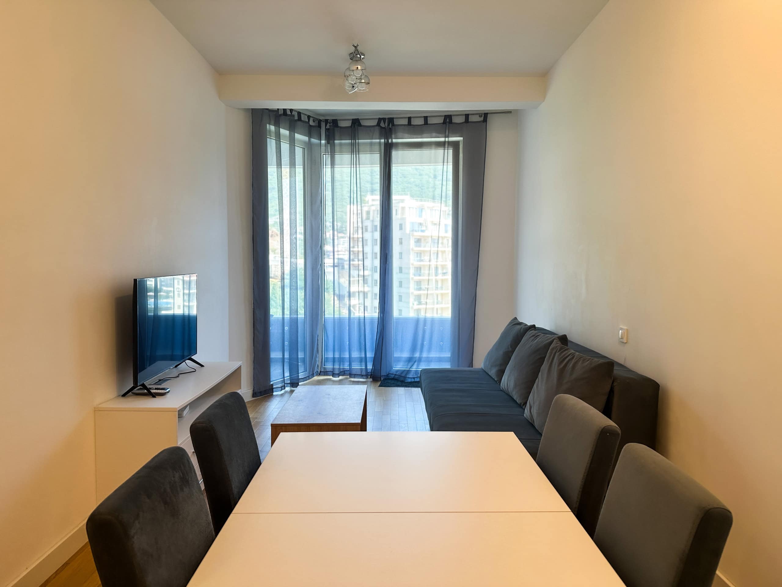 Living room with furniture, dining table, and panoramic window in an apartment in Bečići, Montenegro.