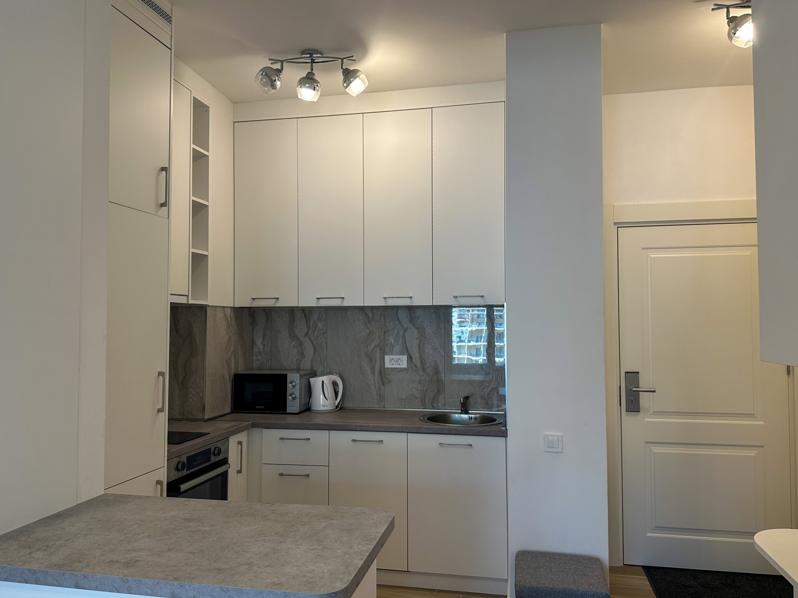 White kitchen with furniture, appliances, and stone-look backsplash in an apartment in Bečići, Montenegro