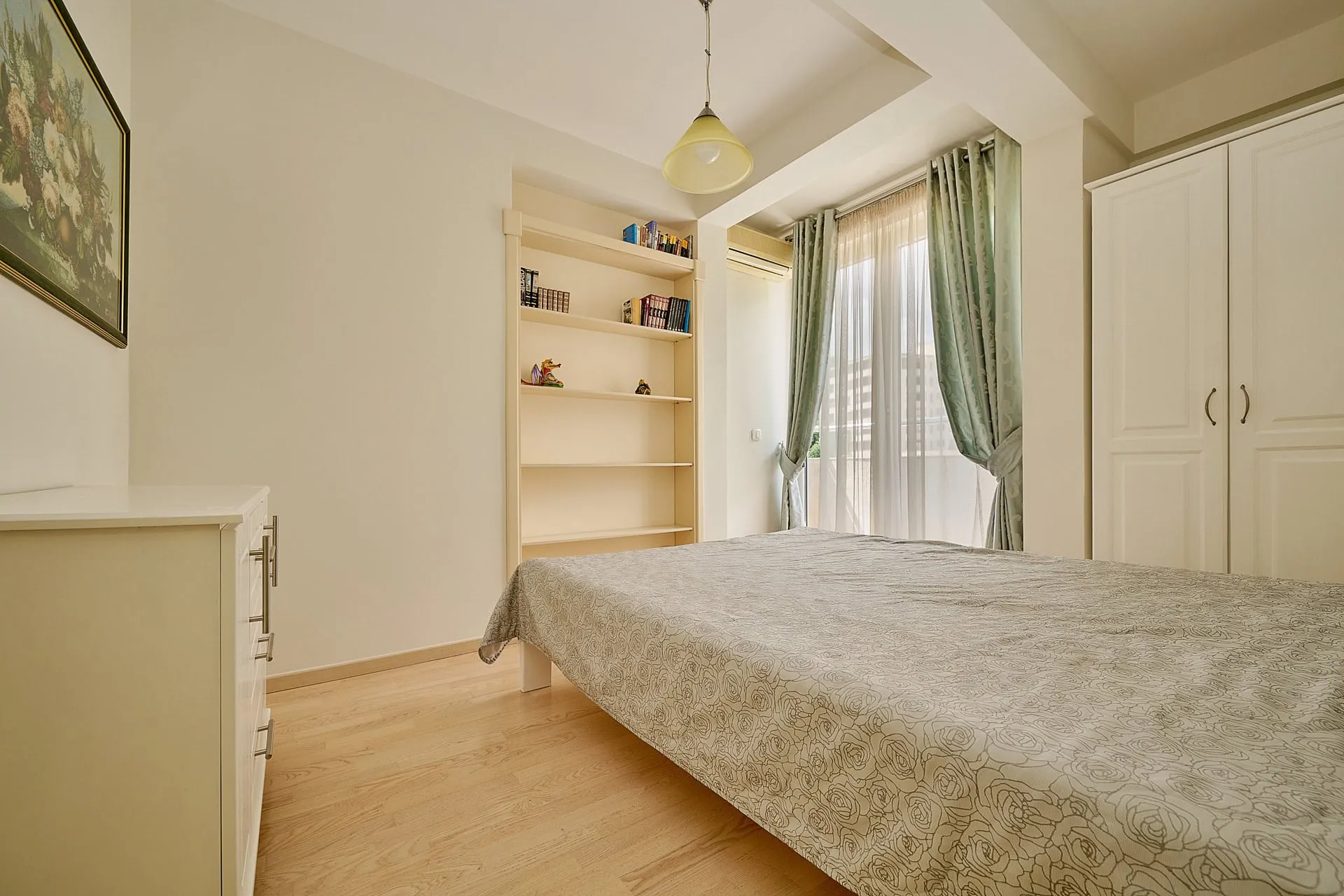 Bedroom featuring a bed, white wardrobe, bookshelf, and light wood flooring.