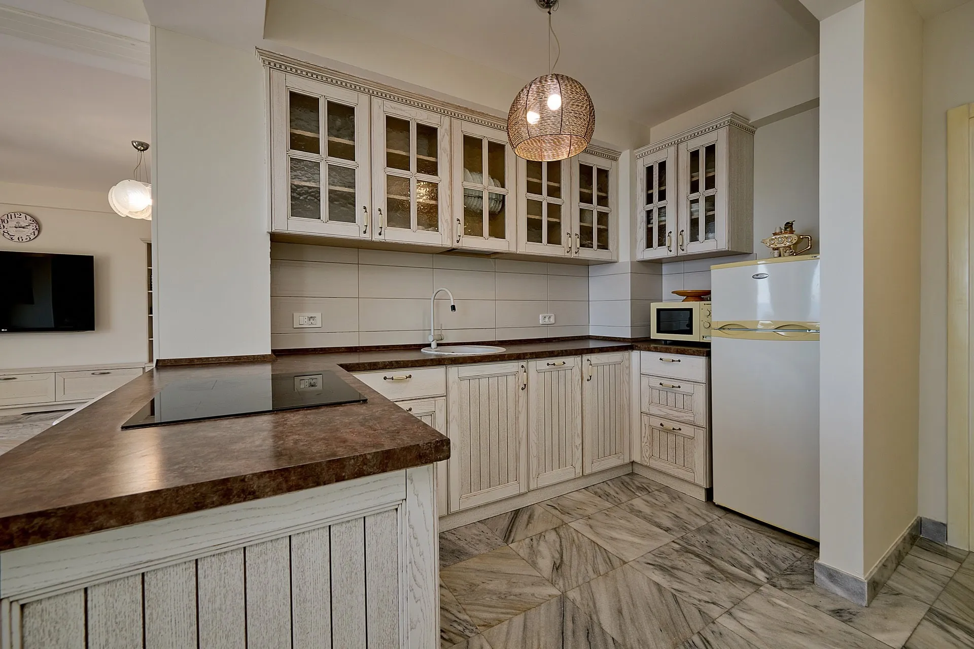 Kitchen with light wood cabinets, dark countertop, induction cooktop, sink, and refrigerator visible.
