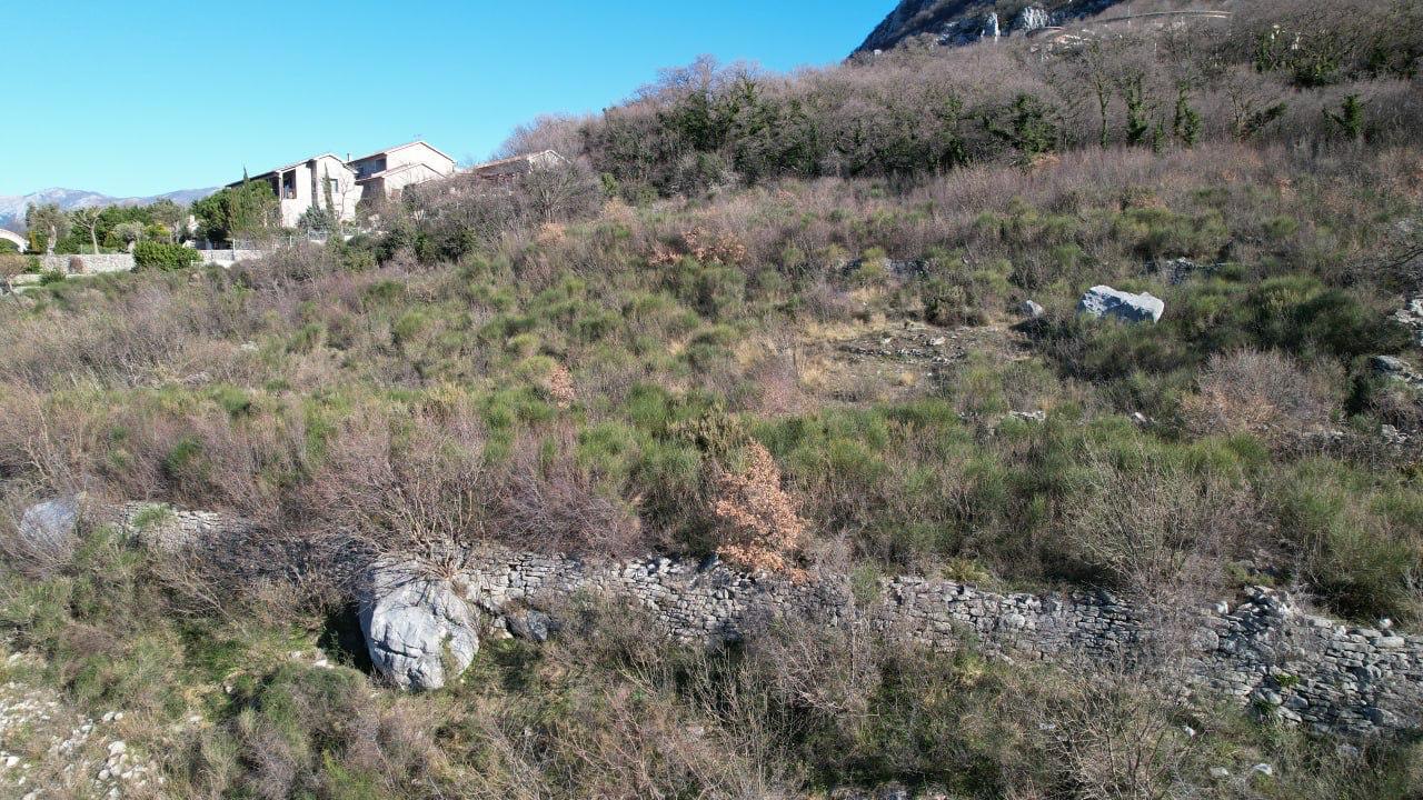 Land plot for construction in Blizikuće, Montenegro: terraced terrain with stone masonry and mountain views.