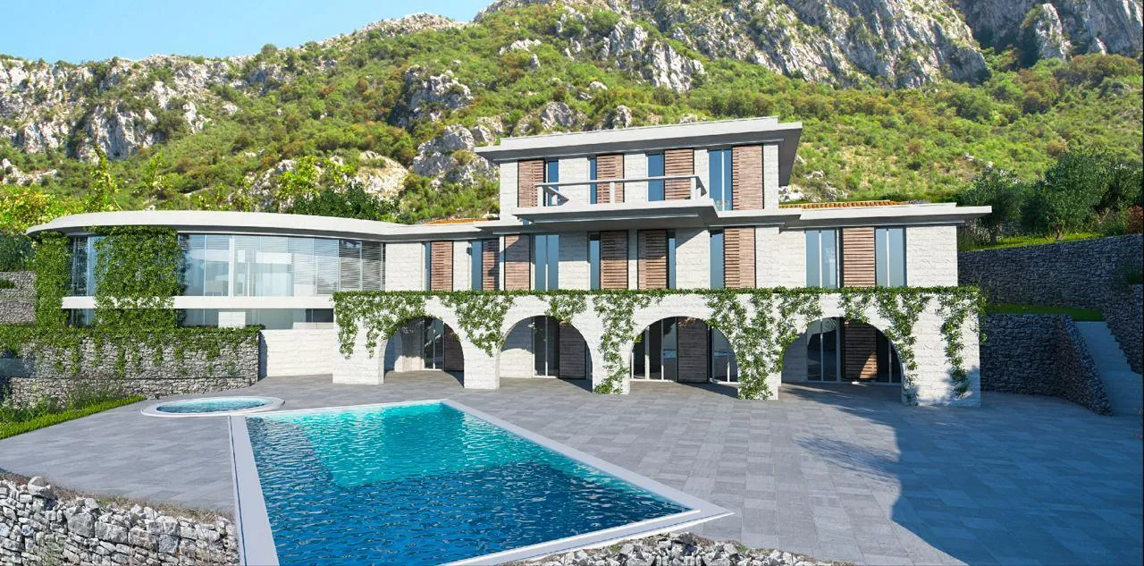 Modern house with a large swimming pool in the foreground and stone arches, surrounded by mountains.