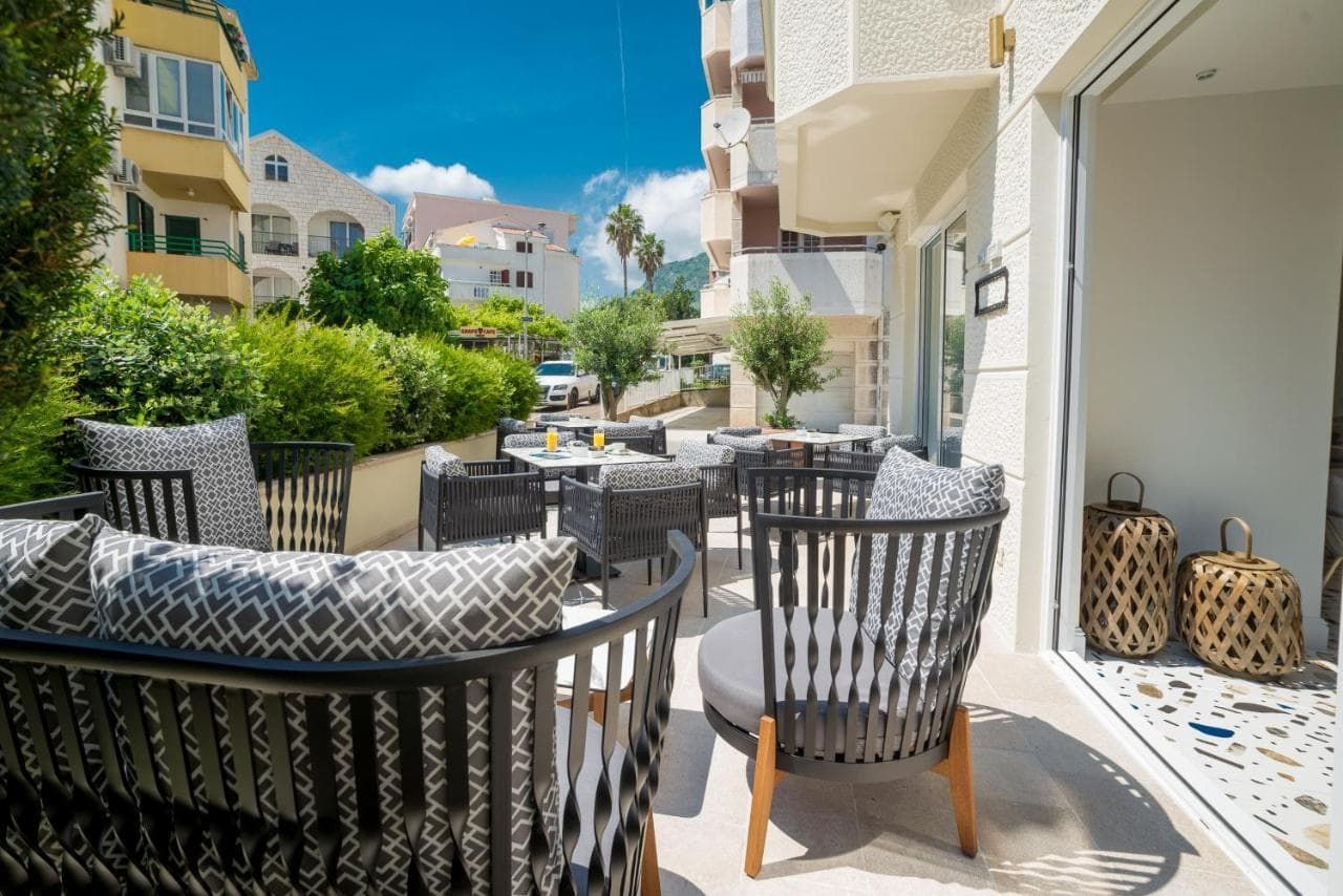 Cozy terrace with wicker furniture at a hotel in Budva, Montenegro: city view, modern design, and lounge area.