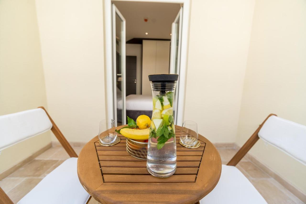 Cozy balcony with a wooden table and fruit in a hotel in Budva, Montenegro, overlooking the modern room interior.