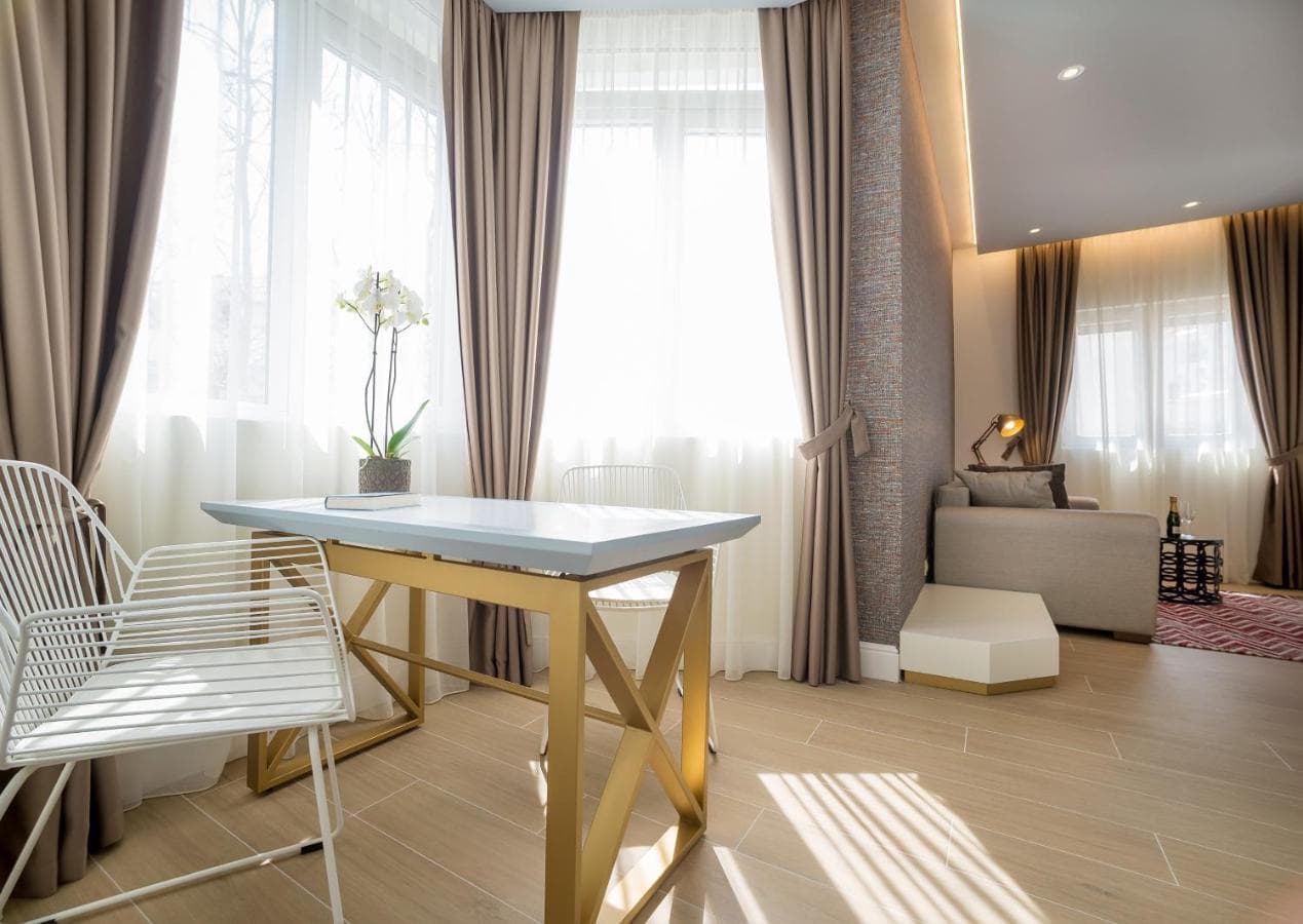 Modern hotel living room in Budva, Montenegro: a designer table with gold legs, a soft sofa, and panoramic windows.