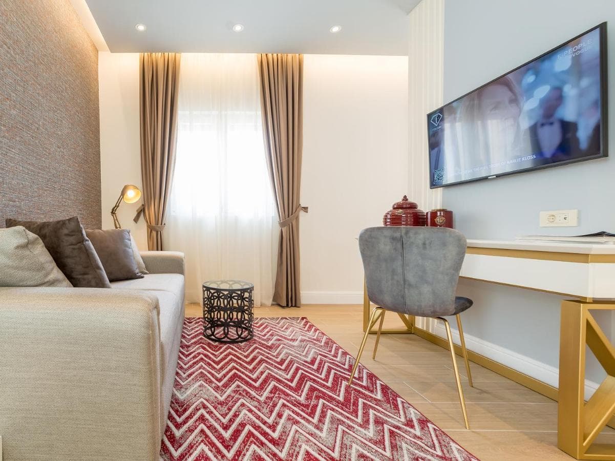 Cozy living room in a hotel in Budva, Montenegro: modern furniture, TV, a rug with a zigzag pattern, and stylish decor.
