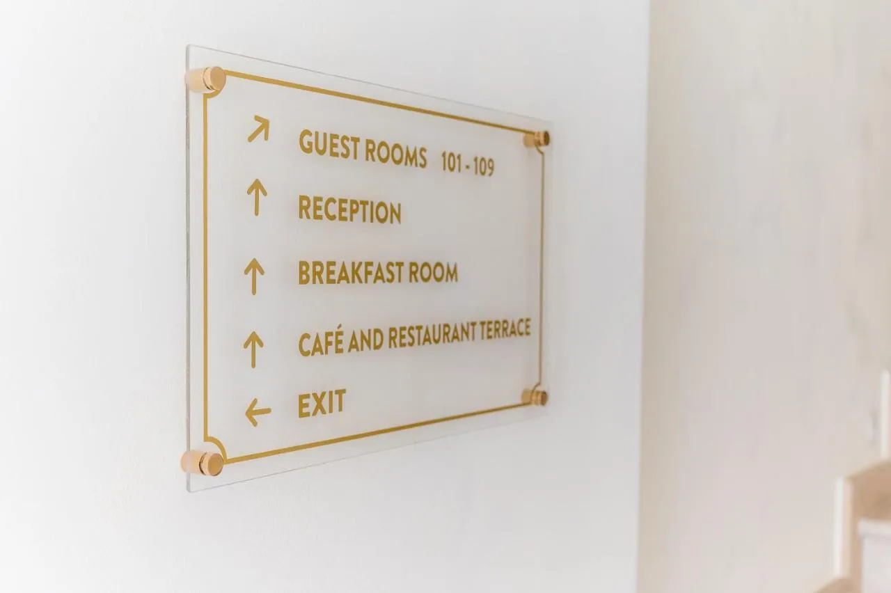Directional hotel sign on a white wall pointing to guest rooms, reception, breakfast room, and cafe.