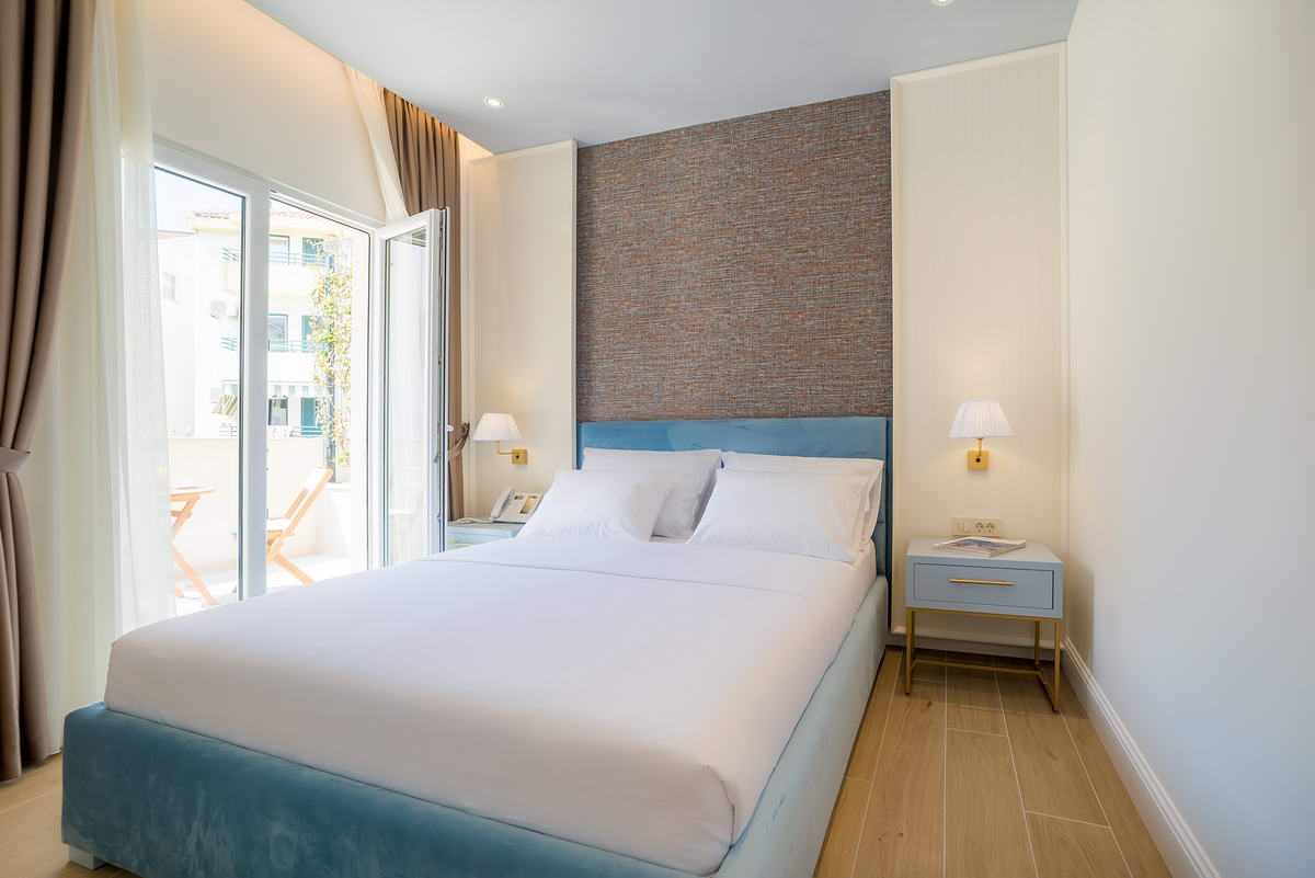 Modern bedroom in a hotel in Budva, Montenegro: double bed, accent wall, and access to the balcony.