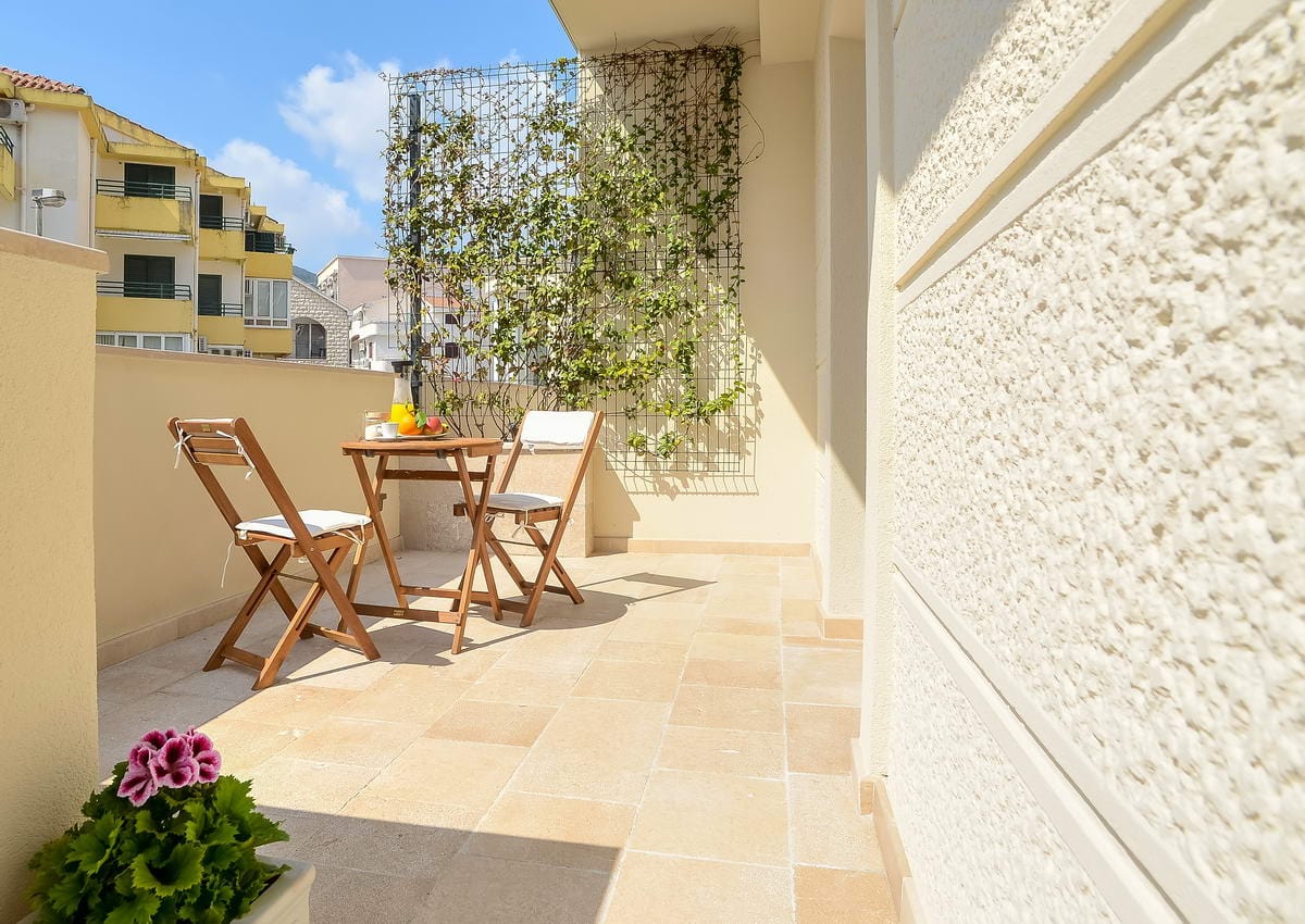 Cozy balcony with wooden furniture and climbing plants in a hotel, Budva, Montenegro.