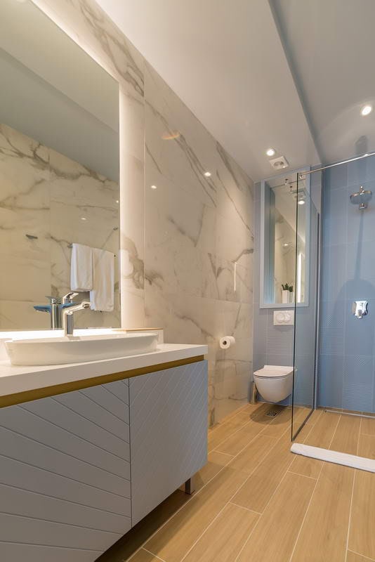 Modern bathroom in a hotel in Budva, Montenegro: marble-style finishes, a shower cabin, and a stylish vanity with sink.