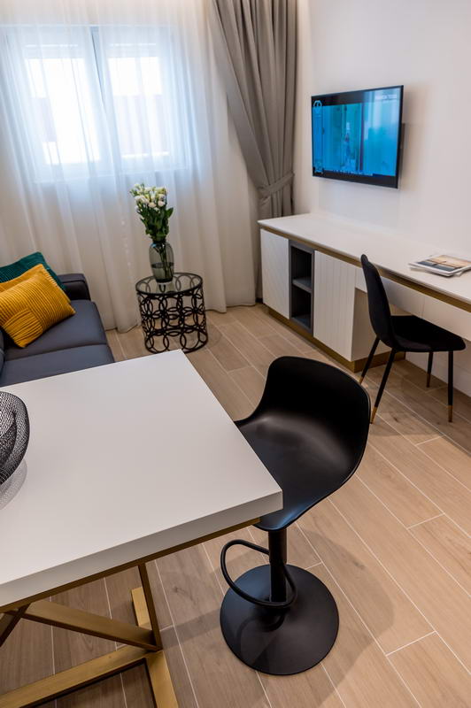 Modern hotel living room in Budva, Montenegro: stylish furniture, dining area, TV, and a bright interior.