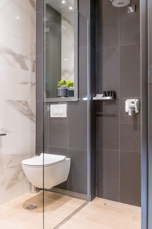 Modern bathroom in a hotel in Budva, Montenegro: shower cabin, wall-mounted toilet, and marble-look tile finish.