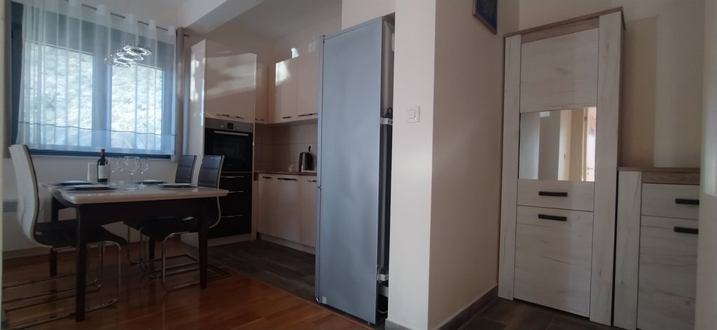 Modern kitchen-dining area in an apartment in Bečići, Montenegro: light-colored kitchen set, dining zone, and built-in appliances.