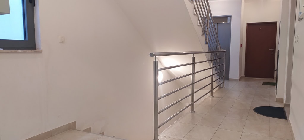 Modern entrance with stairs and metal railings in a residential complex, Bečići, Montenegro.