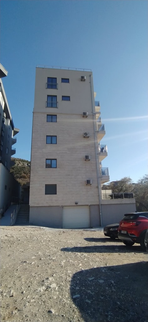 Modern residential building with balconies and parking in Bečići, Montenegro: view of the building facade with the surrounding area.