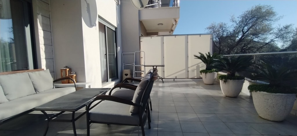 Spacious terrace with garden furniture and plants in an apartment in Bečići, Montenegro. View of the balcony with tiles.