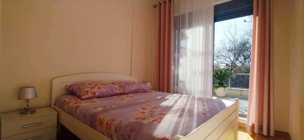 Cozy bedroom with a double bed and balcony access in an apartment in Bečići, Montenegro.